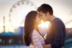 romantic couple in front of santa monica amusement park at sunset.