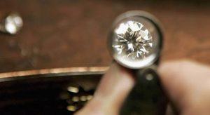 Jeweller inspecting diamond with magnifying glass