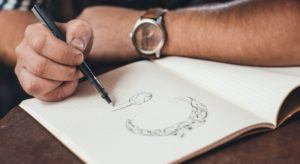 Man designing diamond ring in sketchbook